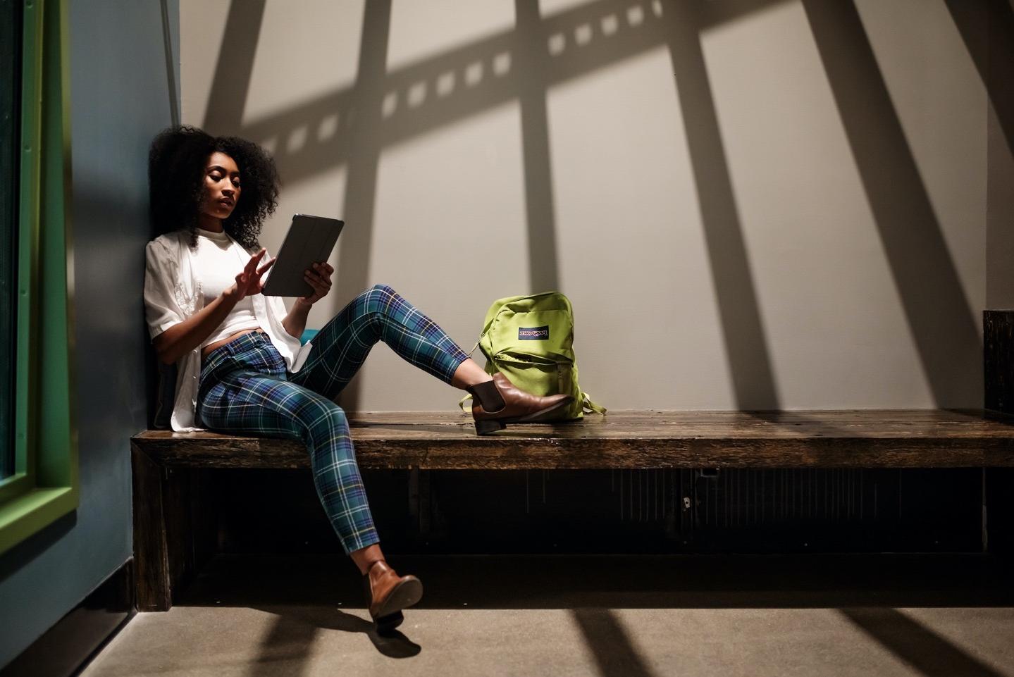 Stylish woman holding tablet & sitting on a bench
